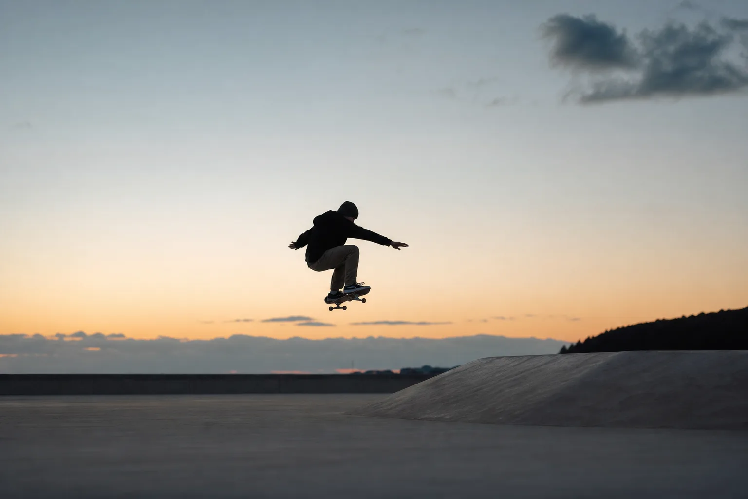 Skateboardåkare mitt i ett hopp på en tom betongyta