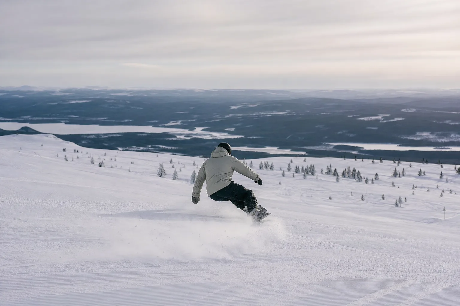 Åkare i mitten av en sväng i pisten med snöspray vid kanten