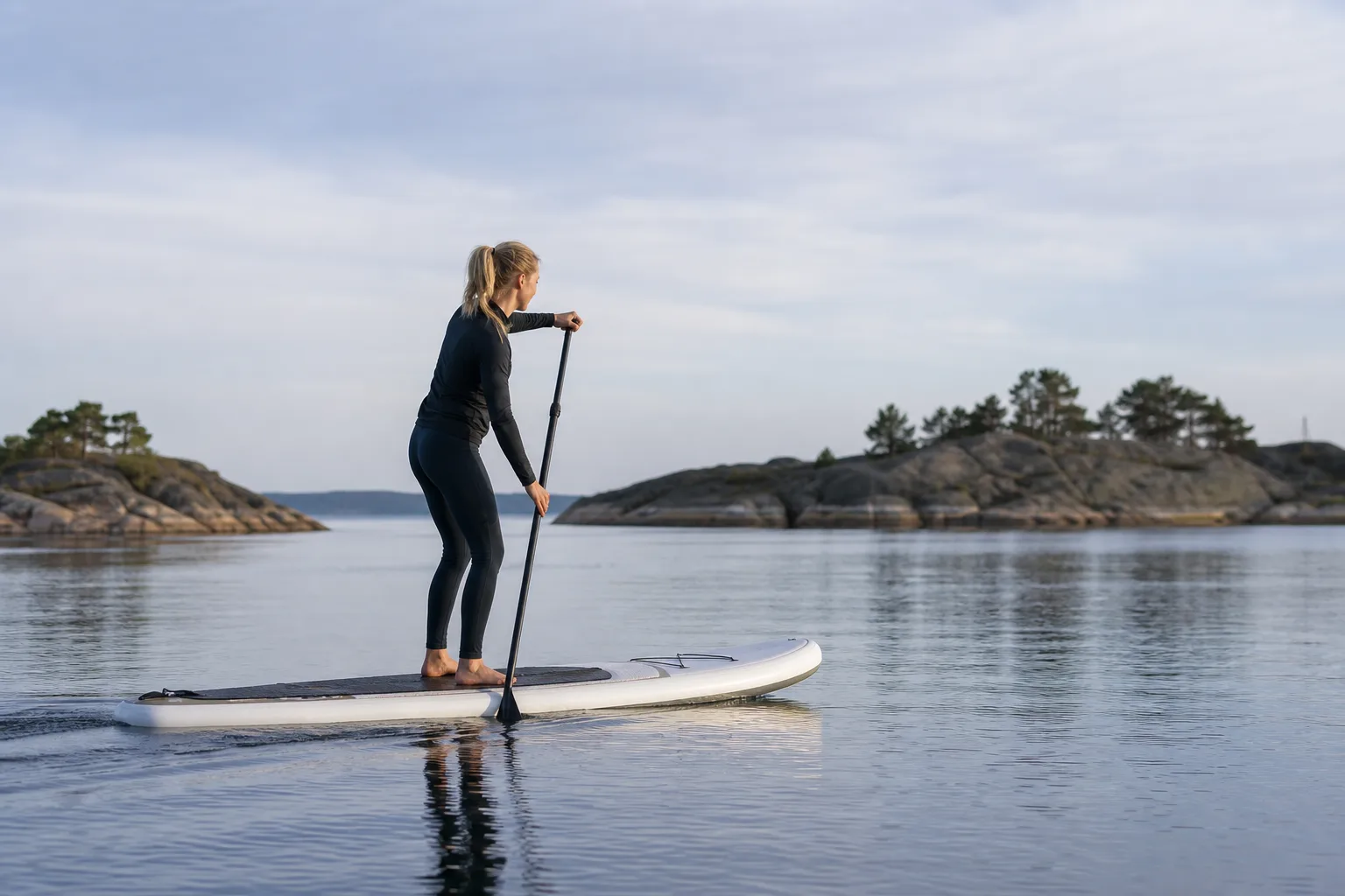 Person som paddlar stående på en SUP-bräda med bålrotation i paddeltaget på lugnt vatten