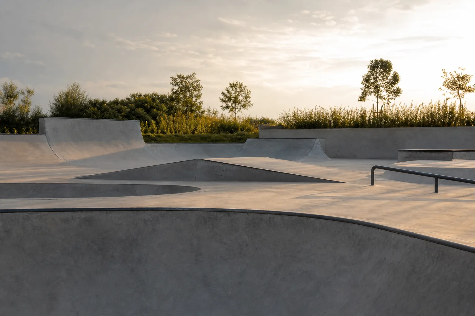 Tom betongskatepark med bowl och räls i eftermiddagsljus